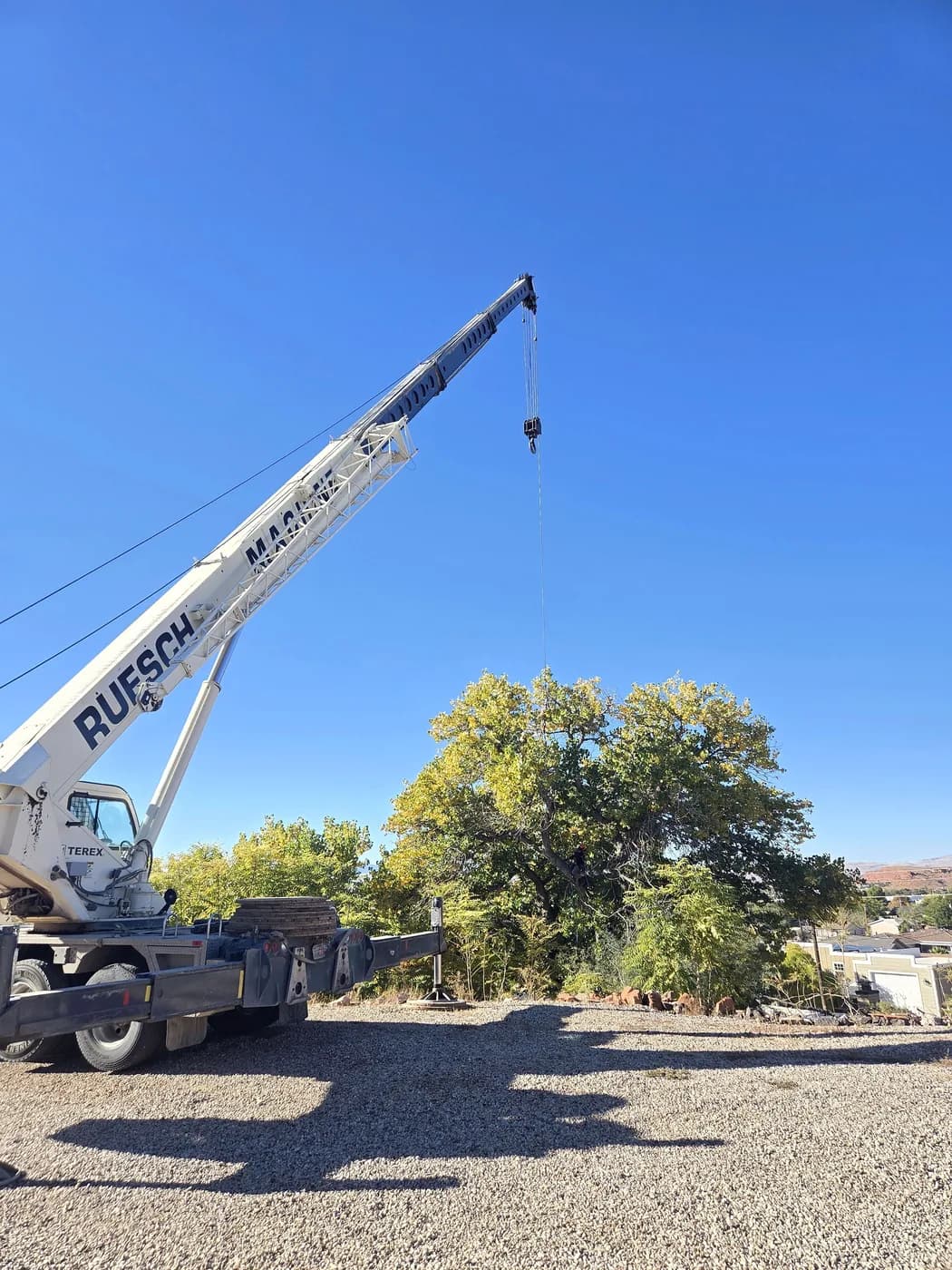 A crane set up with its boom extended over a desert yard
