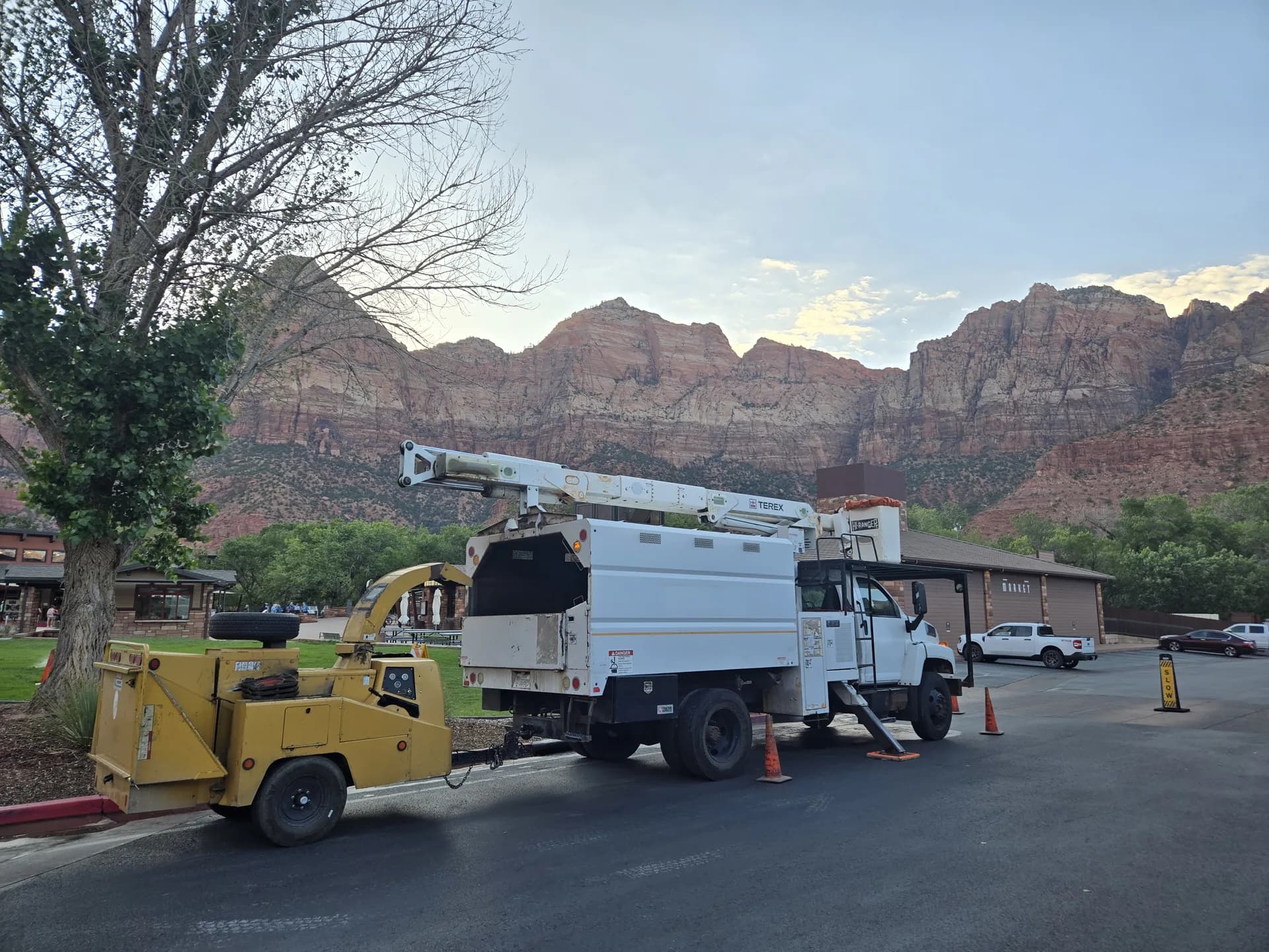 Crew truck and wood chipper parked on a job under red rock cliffs